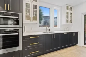 Two tone kitchen with charcoal base cabinets, white uppers, and gold handles