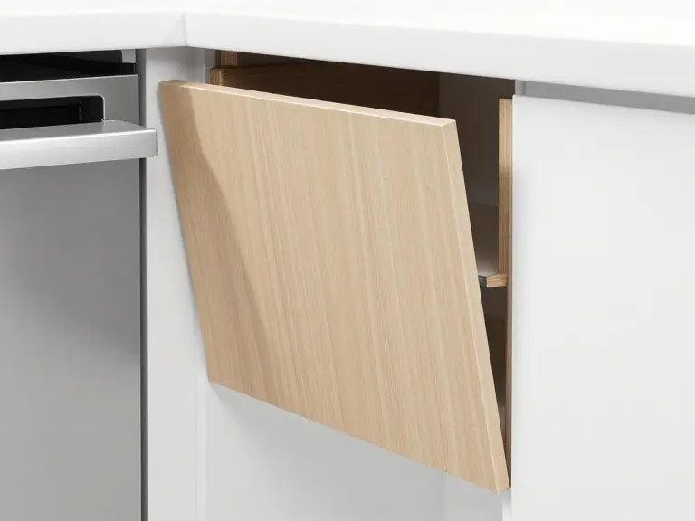 Close-up of a cabinet door corner where the surface film has started to lift near a dishwasher.